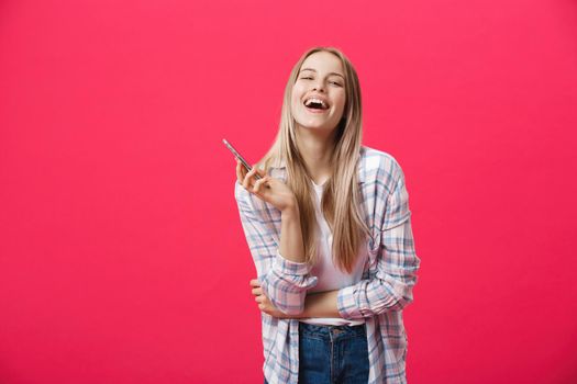 Cheerful young woman talking on mobile phone isolated on pink background.