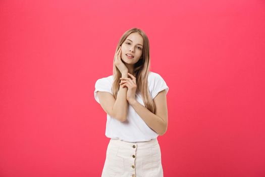 Attractive young girl touching her face. Photo of blonde girl with perfect skin on pink background. Beauty and Skin care concept.