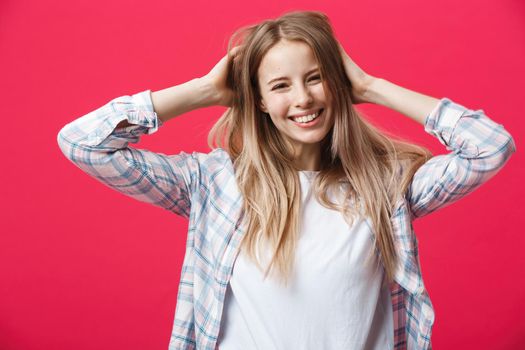 Gorgeours young Caucasian woman with healthy clean skin and beautiful set of features over pink background looking at camera with shy charming smile