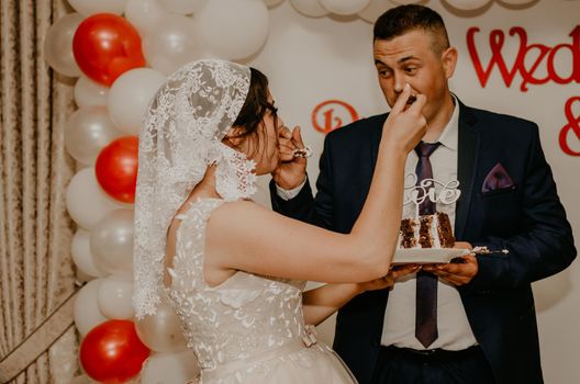 groom and bride at wedding cut their large multi-tiered white cake taste it fed from each other. Slavic Ukrainian Russian traditions