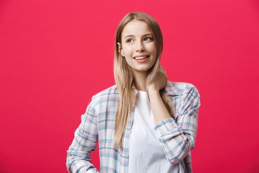 Gorgeours young Caucasian woman with healthy clean skin and beautiful set of features over pink background looking at camera with shy charming smile