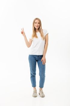 Full length portrait of a happy young woman standing and showing peace gesture with two hands isolated over white background.