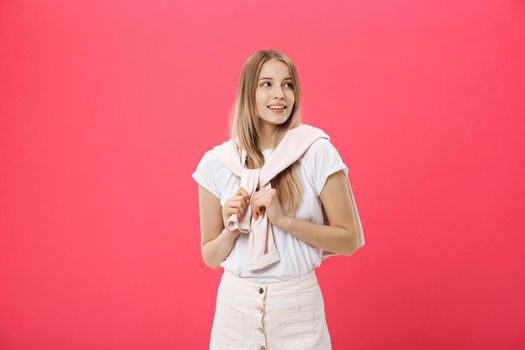 Cheerful beautiful young woman in pink sweater over pink background.