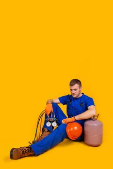 A male worker in overalls sits on the floor with a suppressed feeling of unemployment, problems of the economy from the economic downturn. The concept of the economic crisis, unemployment