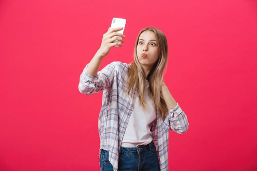 Charming young woman in white hat travel and take selfie on front camera smartphone posing isolated on shine pink background.