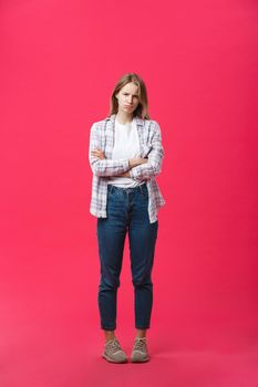 Thoughtful frowning young woman standing and thinking over pink background.