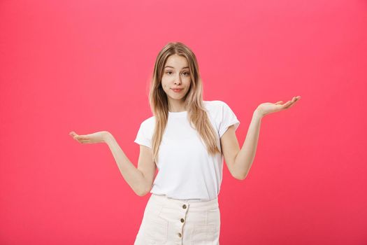 Emotional beautiful and positive young woman with boring face looks forward, spreading her hands to the side against a pink background