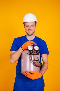 A male air conditioning repairman is holding a freon cylinder in his hands to air-condition the air conditioner. Refueling freon air conditioners.