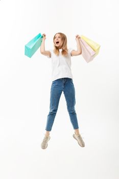 Full length portrait of a happy pretty girl holding shopping bags while jumping and looking at camera isolated over white background.