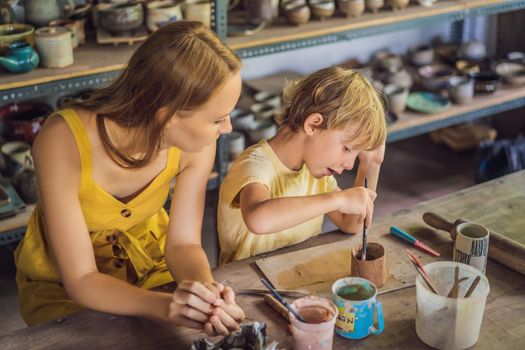 mother and son doing ceramic pot in pottery workshop.