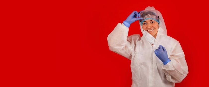 A young woman in a protective suit takes off a medical mask. Woman smiling looking at camera. Healthcare and medical concept.