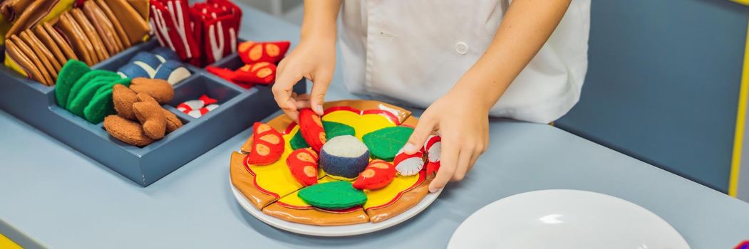 The boy plays in the toy kitchen, cooks a pizza. BANNER, LONG FORMAT