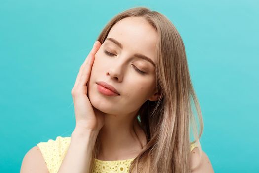 Beautiful Woman Face Portrait Beauty Skin Care Concept: beauty young caucasian female model girl touching her face skin cheeks hands fingers. Fashion Beauty Model isolated on blue