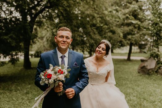 blonde European Caucasian young man groom in blue suit and black-haired woman bride in white wedding dress with long veil and tiara on head. first meeting newlyweds groom wait sees bride