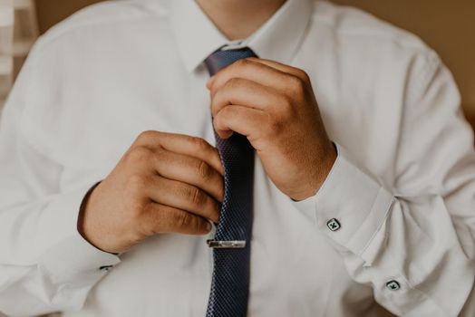 blonde European Caucasian young groom in shirt business suit with tie prepare for wedding. a man preparing for an important event a meeting indoors worries