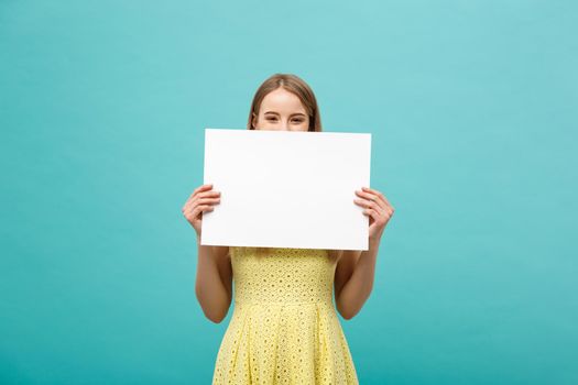 Beautiful woman holding a blank billboard isolated on blue background.