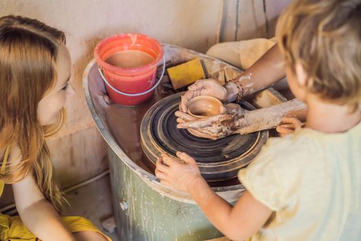 mother and son doing ceramic pot in pottery workshop.