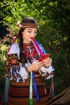 Ukrainian woman in an embroidered shirt holds a mobile phone in her hands.