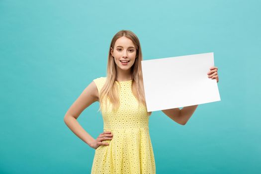Portrait beautiful young caucasian woman holding a blank paper isolated on pastel blue background.