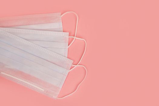 Medical mask for protection against flu and coronavirus on a pink background. Prevention of the spread of the virus and the pandemic COVID-19.