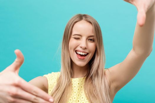 Close-up Young Caucasian woman face and eye care and she making frame with hands isolated over pastel blue background