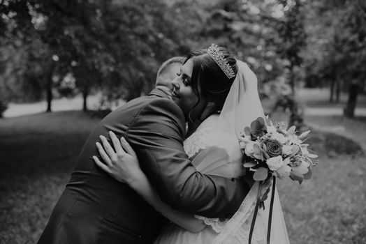 blonde European Caucasian young man groom in blue suit and black-haired woman bride in white wedding dress with long veil and tiara on head. first meeting newlyweds groom wait sees bride