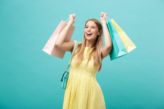 Portrait of young happy smiling woman with shopping bags. Blue Background