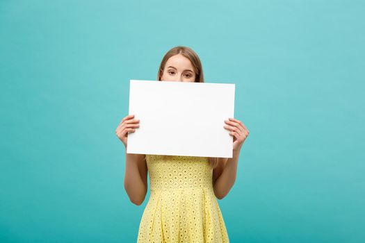 Beautiful woman holding a blank billboard isolated on blue background.