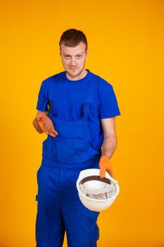 Overweight worker holds out a blank white safety helmet. Recession in the economy. A man in a jumpsuit without work. Recession and the economic crisis, unemployment.