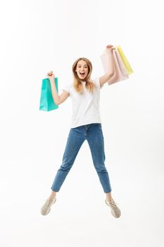 Full length portrait of a happy pretty girl holding shopping bags while jumping and looking at camera isolated over white background.