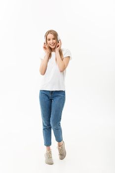 Lifestyle Concept: Portrait of a cheerful happy girl student listening to music with headphones while dancing isolated over white background.