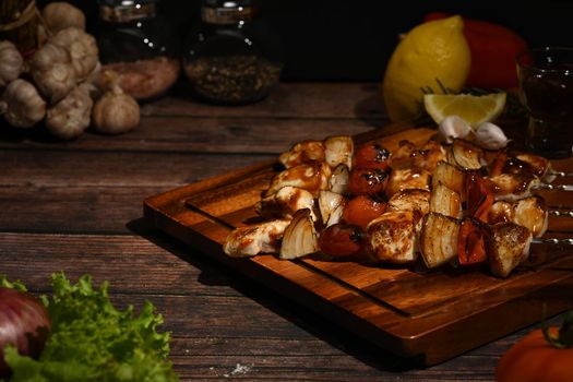 Grilled chicken skewers with cherry tomato and sweet pepper and onions on wooden plate. Barbecue, food, holiday concept.