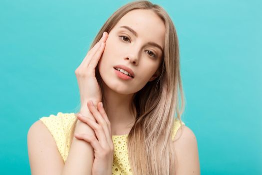 Beautiful Woman Face Portrait Beauty Skin Care Concept: beauty young caucasian female model girl touching her face skin cheeks hands fingers. Fashion Beauty Model isolated on blue