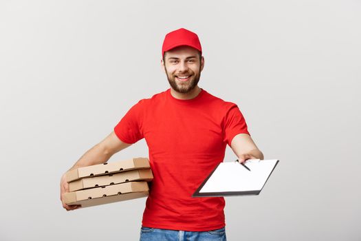 Delivery Concept: Young handsome delivery man with pizza boxes giving you a document to sign.