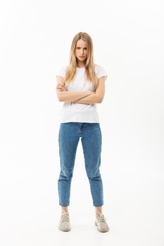 Full length portrait of a pretty young caucasian woman wearing jean and looking upset with her arms crossed.