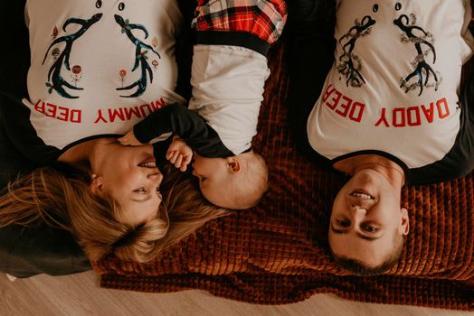 cheerful happy family in pajamas with a child lie on bed in the bedroom. new year family clothes looks outfits. Valentine's Day Celebration Gifts