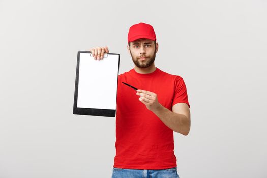 Delivery Concept: Portrait Young caucasian Handsome delivery man or courier showing a confirmation document form to sign. Isolated on Grey studio Background. Copy Space