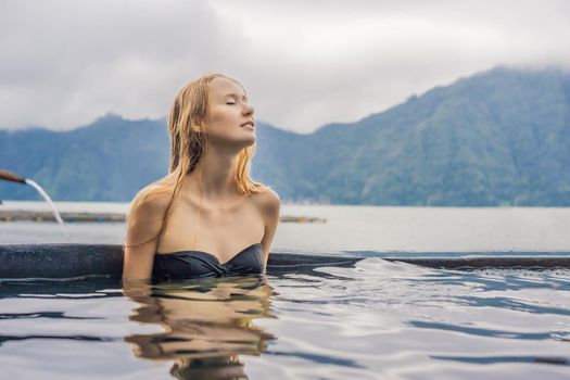 Geothermal spa. Woman relaxing in hot spring pool against the lake. hot springs concept.