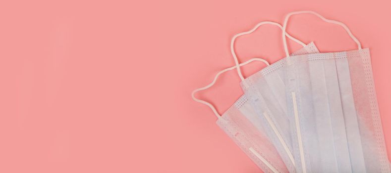 Medical mask for protection against flu and coronavirus on a pink background. Prevention of the spread of the virus and the pandemic COVID-19.