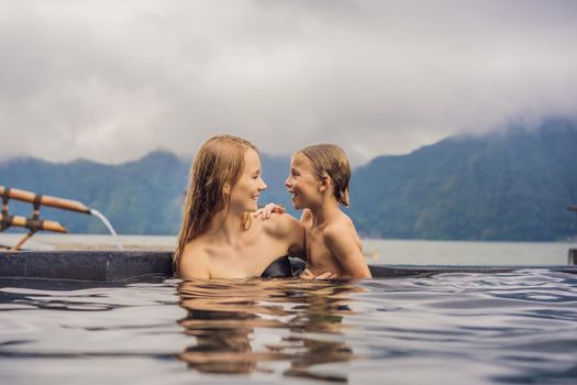 Mom and son travelers in Hot Springs in Bali on the background of lake. Traveling with children concept.