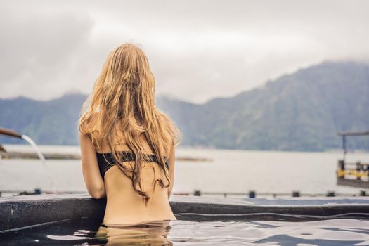 Geothermal spa. Woman relaxing in hot spring pool against the lake. hot springs concept.