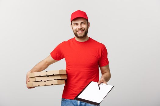 Delivery Concept: Young handsome delivery man with pizza boxes giving you a document to sign.