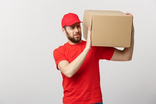 Delivery Concept: handsome Delivery man with boxes, delivery, courier with worry facial expression. Isolated grey background