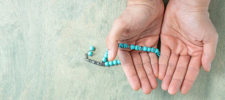 banner with top view on male hands holding rosary beads. Ramadan Kareem background. Muslim man holds a rosary. Flat lay. copy space