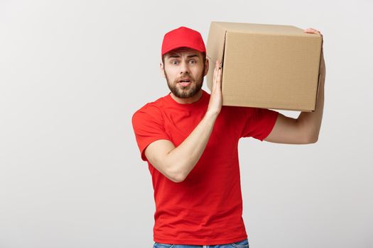 Delivery Concept: handsome Delivery man with boxes, delivery, courier with worry facial expression. Isolated grey background