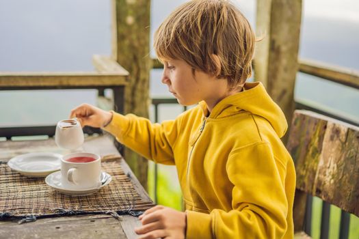 Boy drinking tea in a cafe in the mountains.