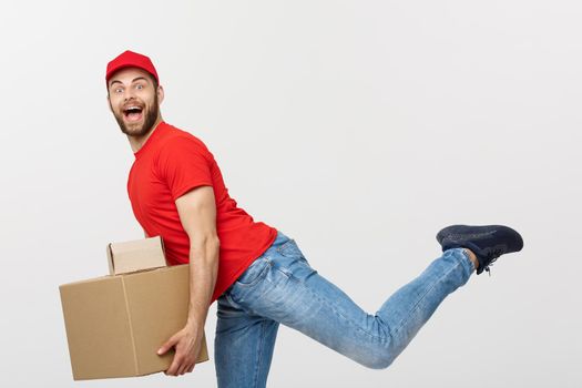 Delivery Concept - Handsome caucasian delivery man rush running for delivering a package for customer. Isolated on Grey studio Background. Copy Space