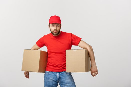 Portrait delivery man in cap with red t-shirt working as courier or dealer holding two empty cardboard boxes. Receiving package. Copy space for advertisement.