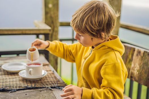 Boy drinking tea in a cafe in the mountains.