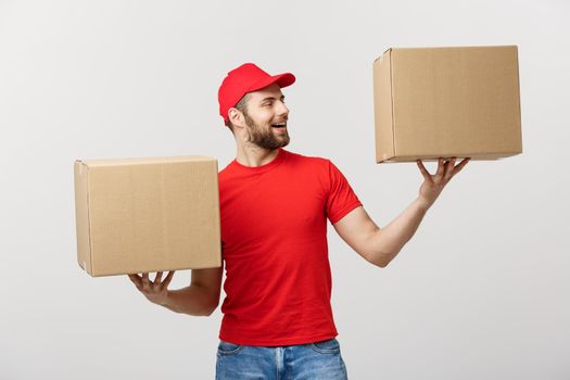 Portrait delivery man in cap with red t-shirt working as courier or dealer holding two empty cardboard boxes. Receiving package. Copy space for advertisement.